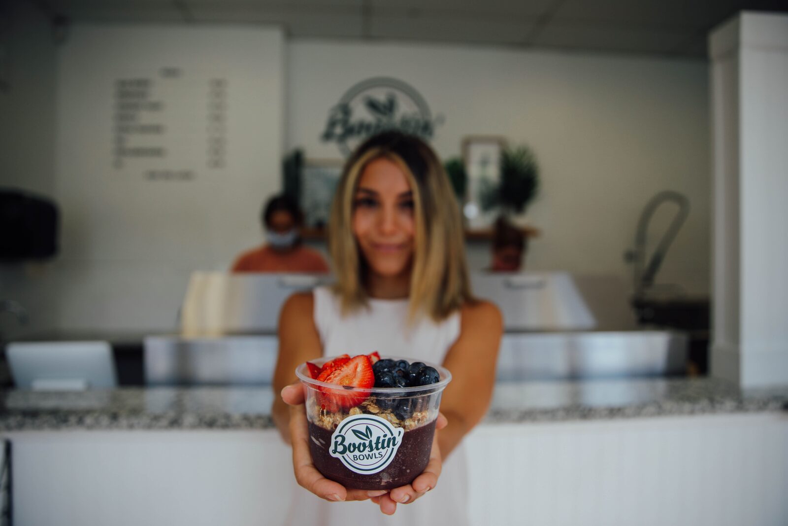 A customer holding an açaí bowl at the counter