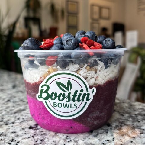 Purple bowl with granola, banana slices, and white coconut shavings