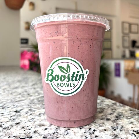Purple acai bowl topped with granola, strawberries, blueberries, banana, and peanut butter