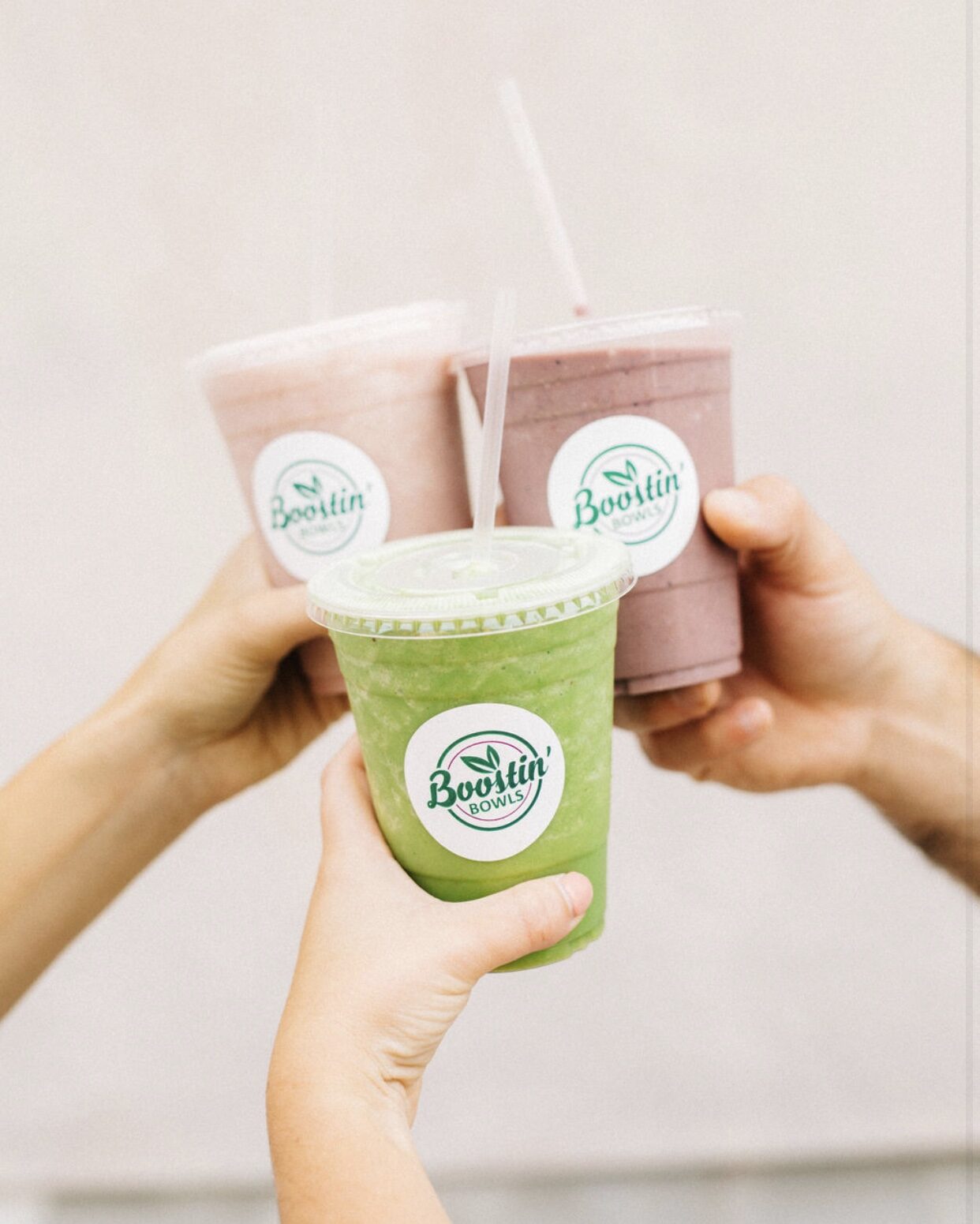 A green smoothie and a berry smoothie touching in a toast