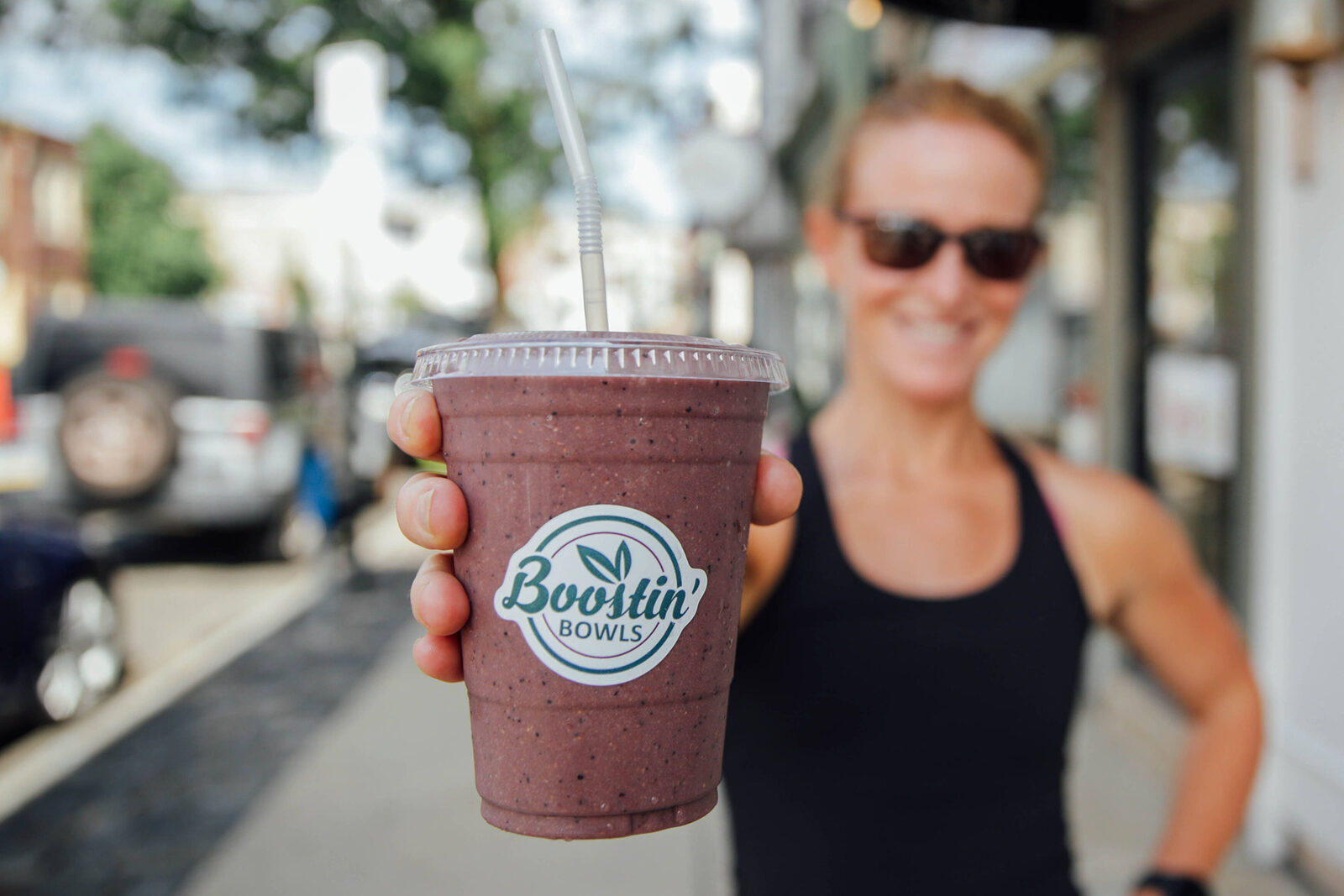 A customer holding a smoothie on the pavement outside the shop